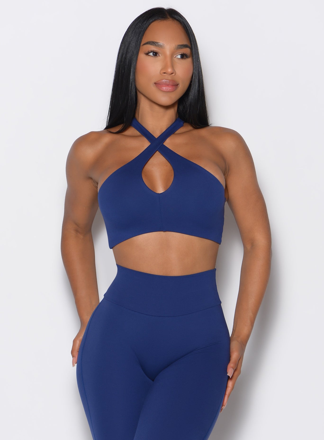 front profile view of a model wearing our Cross Over Halter Bra and the matching leggings in Royal Indigo color