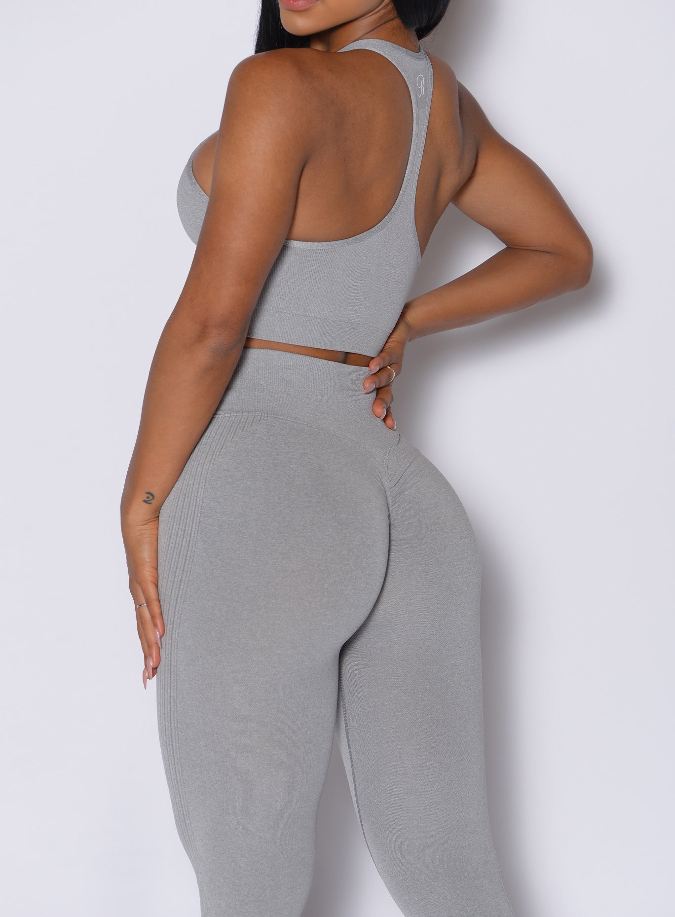 Back side close up view of model wearing the Contour Seamless Leggings and the matching Lifter Heather Seamless Bra in Silver Mist color