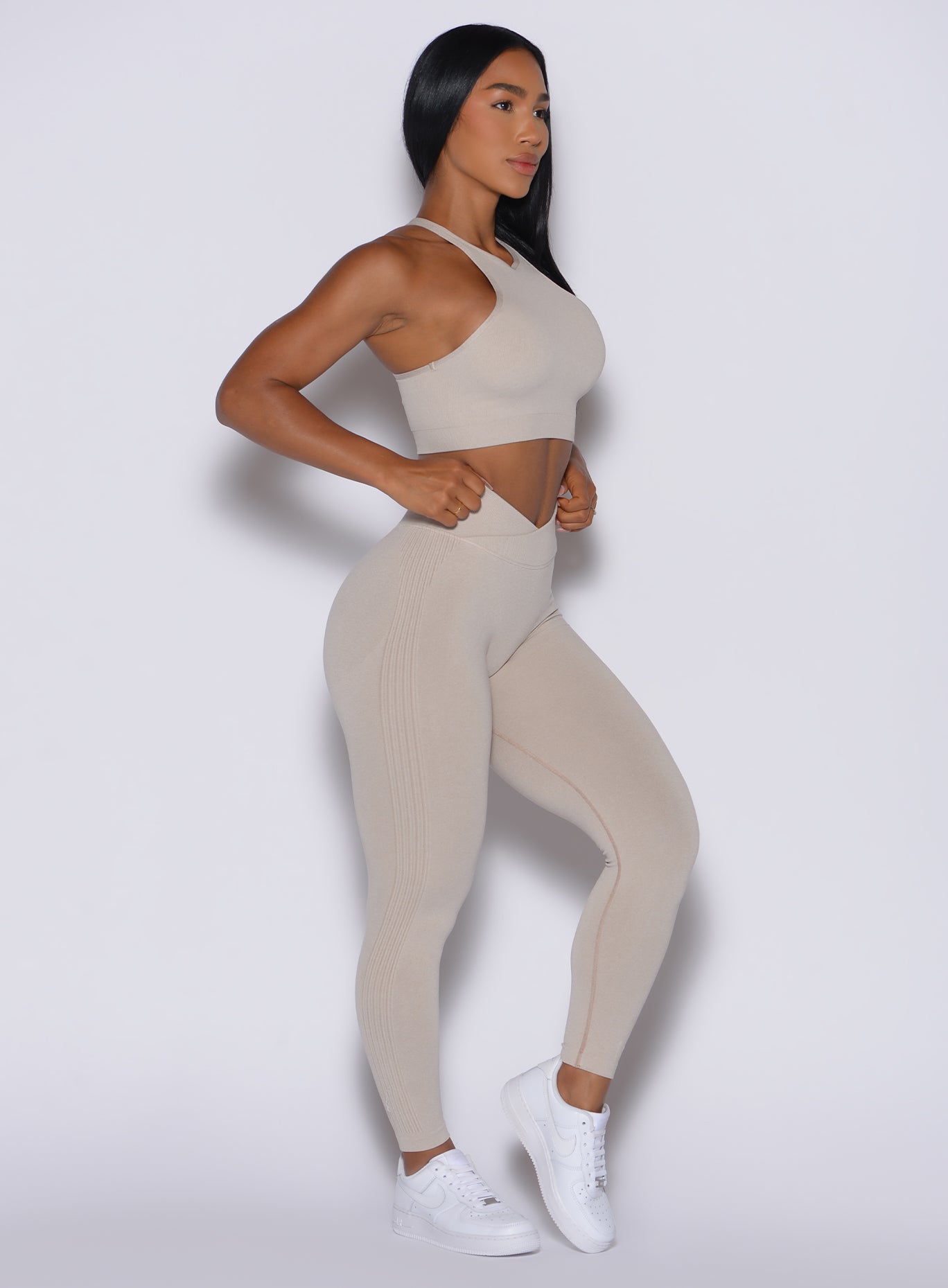 right side profile view of a model facing forward wearing our Contour Seamless Leggings and the matching Lifter Heather Seamless Bra in Oat color