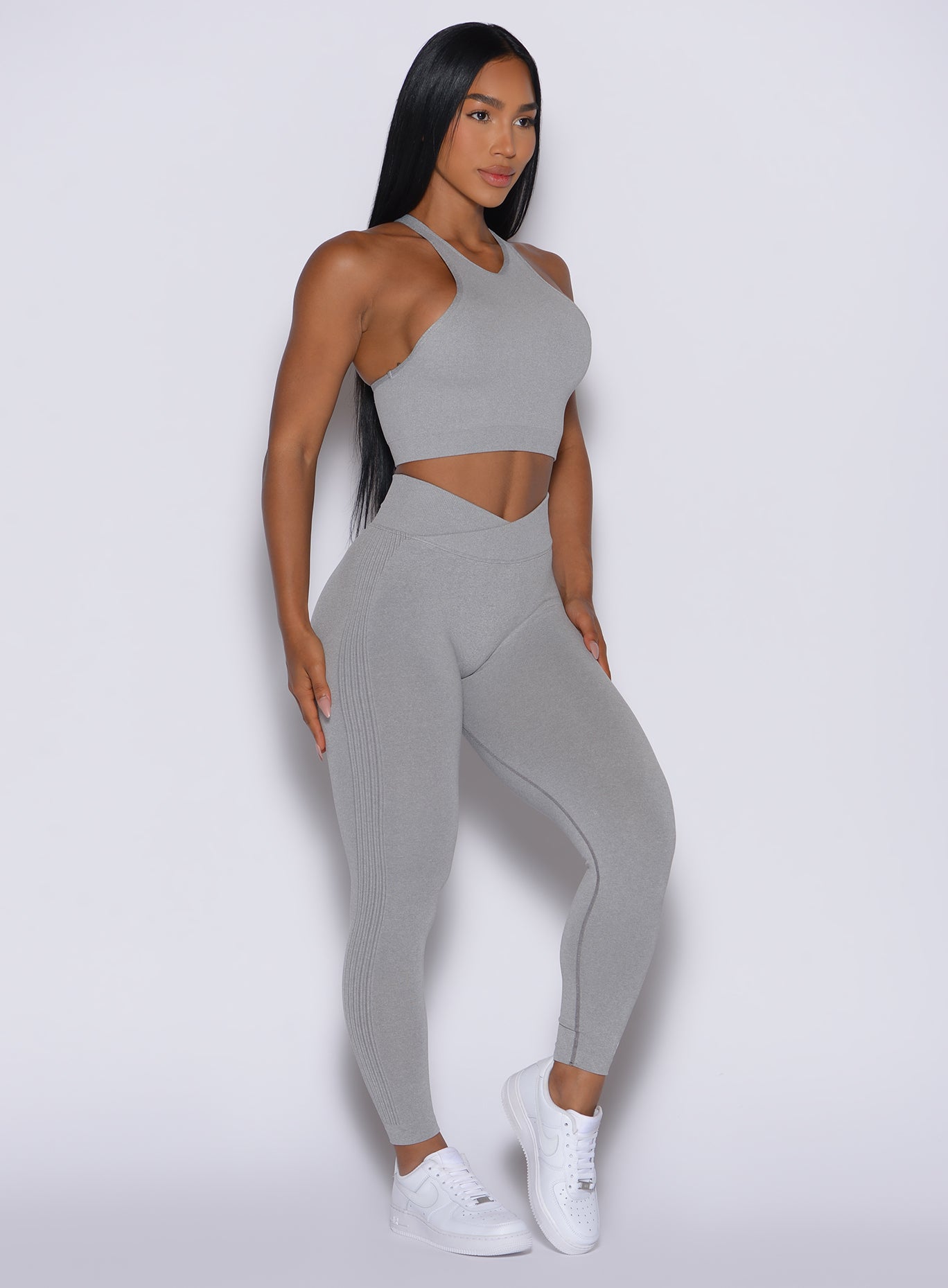 right side profile view of a model facing forward wearing our Contour Seamless Leggings and the matching Lifter Heather Seamless Bra in Silver Mist color