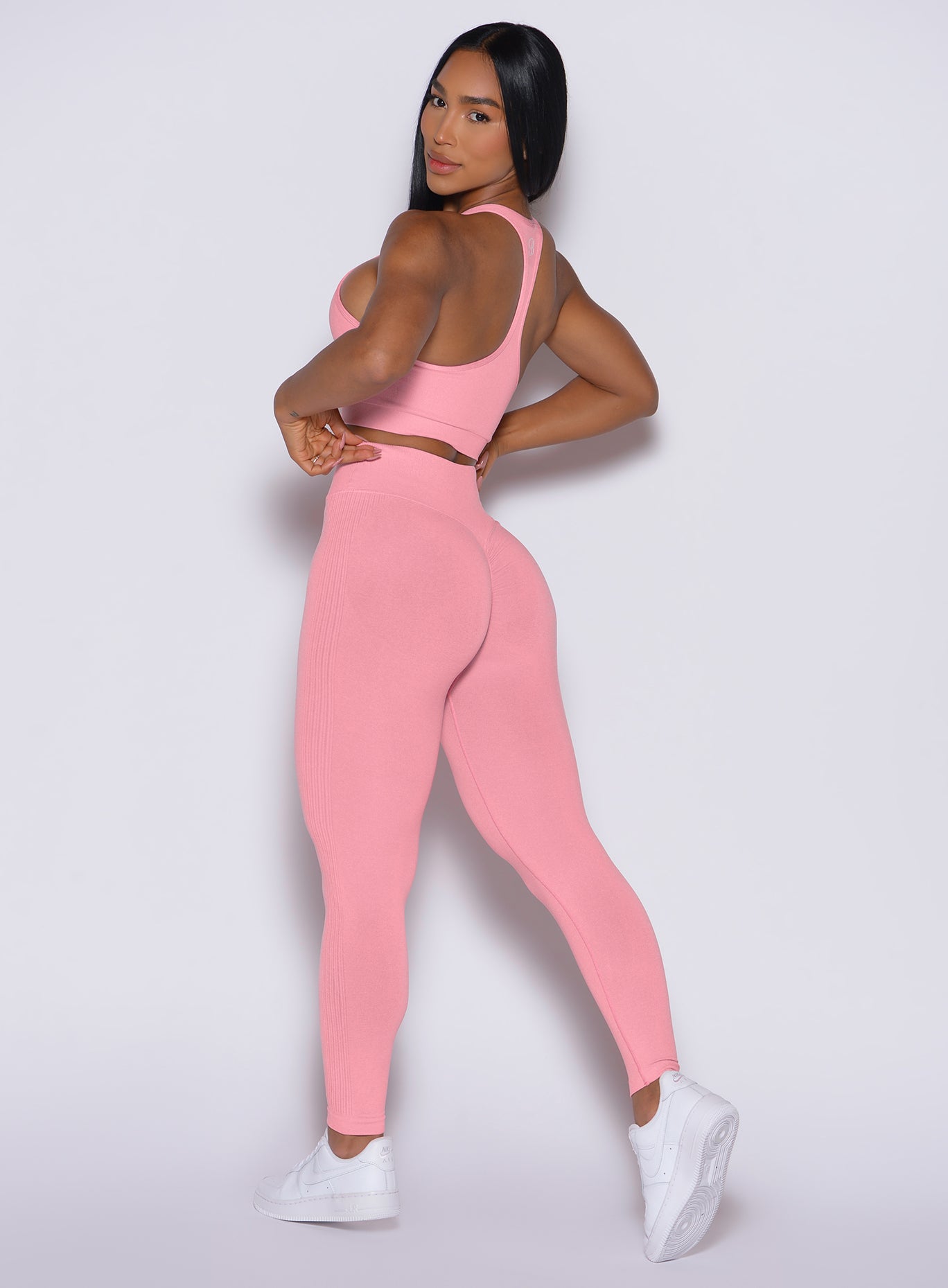 left side view of a model facing to her left wearing our Contour Seamless Leggings and the matching Lifter Heather Seamless Bra in Ballerina color