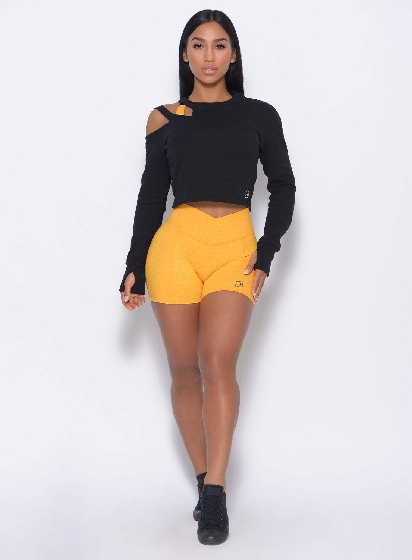 Front profile view of the model in our tiny waist shorts in sunkissed color and a black pullover