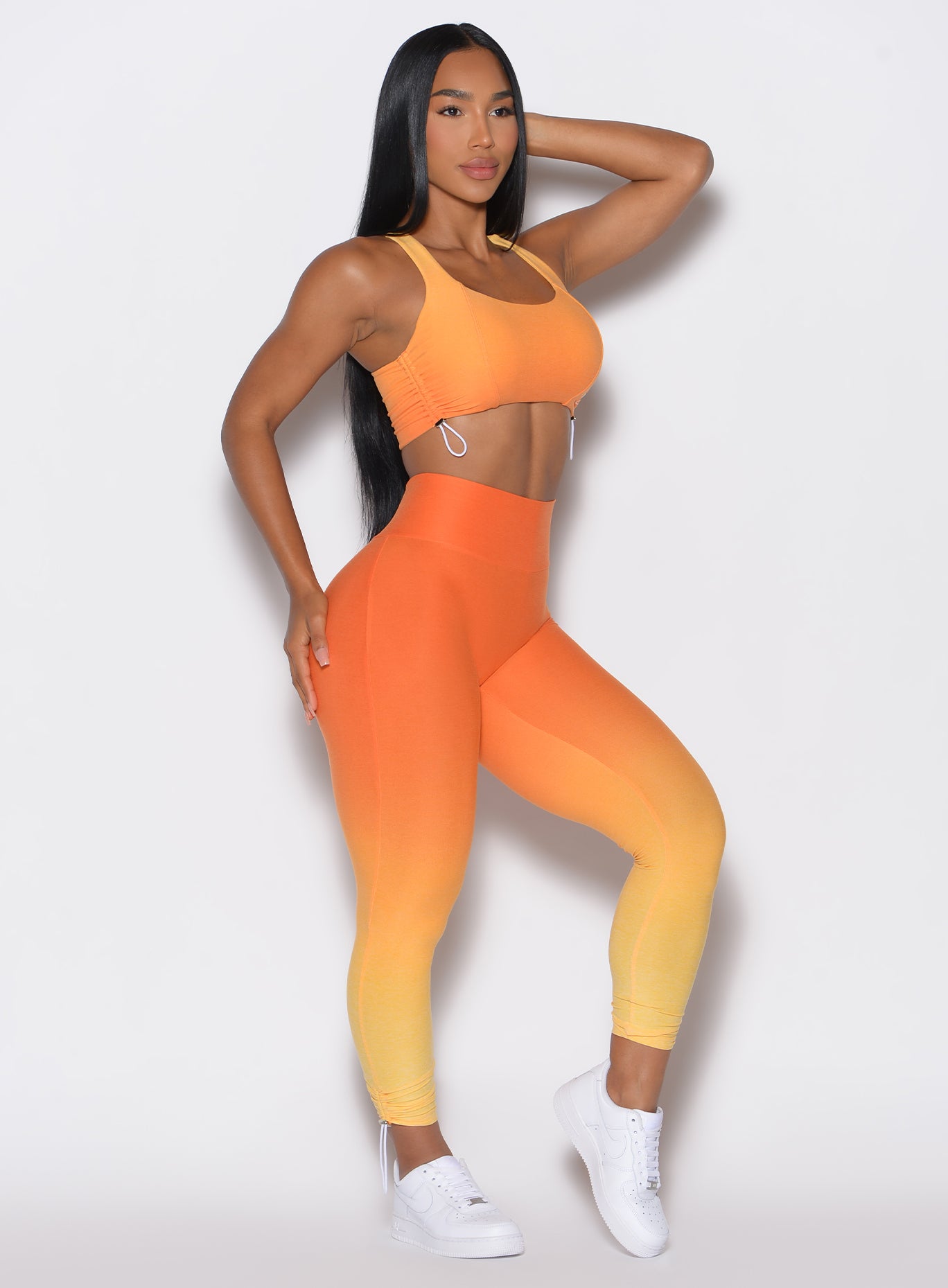 right side profile view of a model angled slightly to her right  wearing our toggle leggings in Ombre Hawaiian Punch color along with the matching sports bra