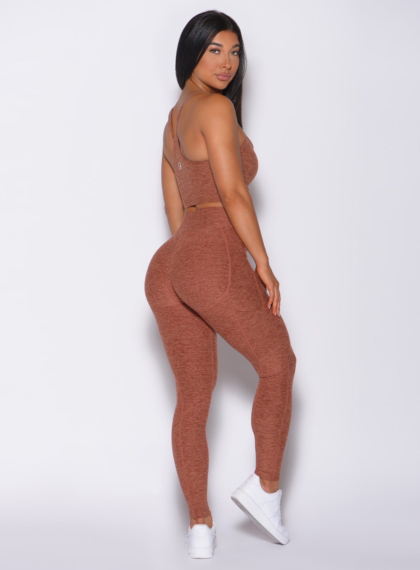 Right side profile view of a model in our uplift pocket leggings in spiced chai color and a matching bra